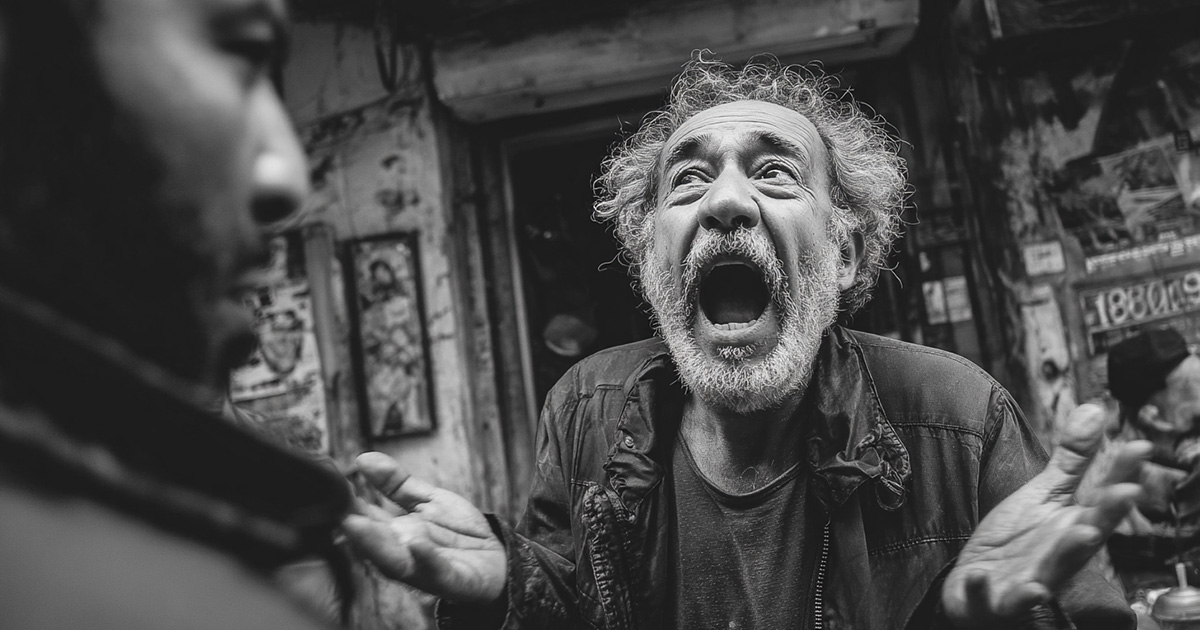 Greek man shouting playfully at a friend outside a taverna
