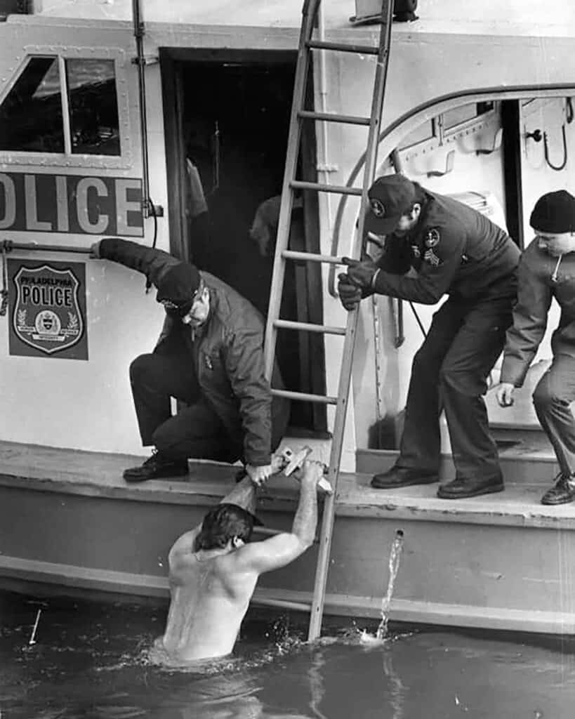 Gus Raptis is helped out of the frigid water by police officers in a boat.
