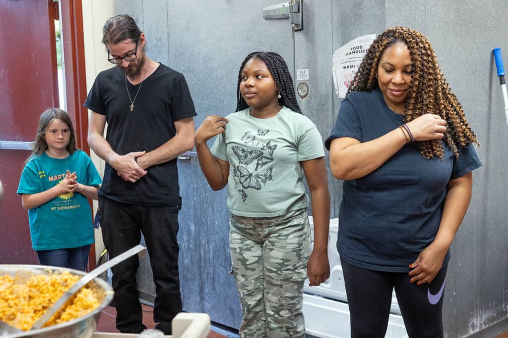 Volunteers join in a group prayer before delivering meals from St. Sophia Church.