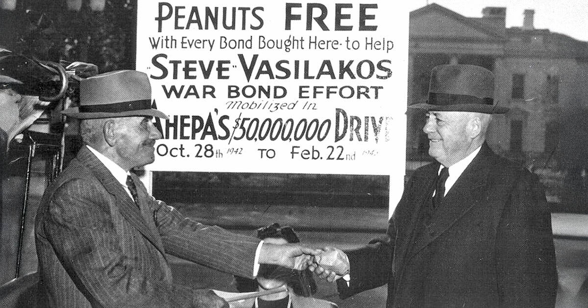 Steve Vasilakos shakes hands with U.S. House Speaker Sam Rayburn in 1942 beside a sign for AHEPA’s $50 million war bond drive.