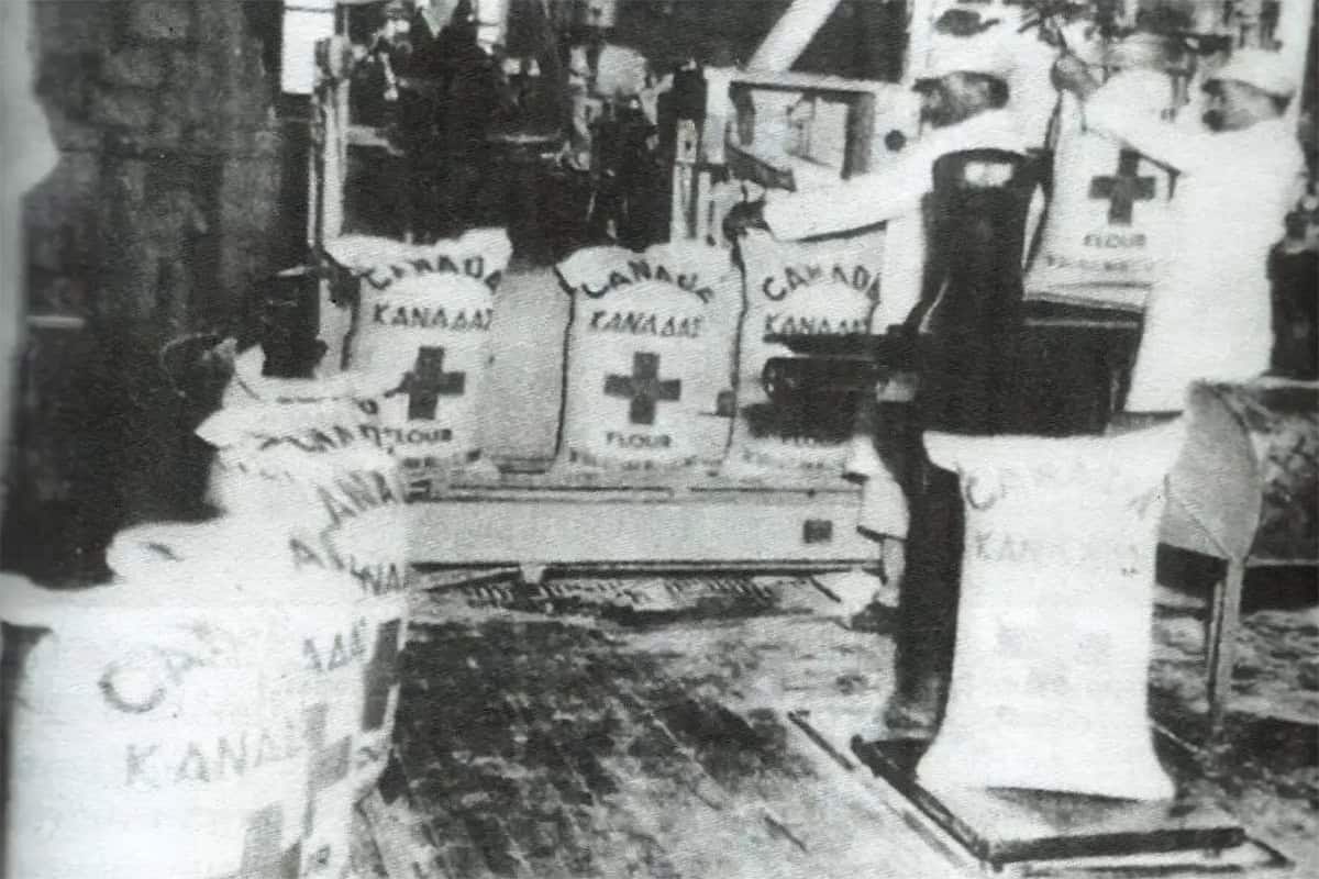 Workers load sacks of Canadian Red Cross flour marked with red crosses onto a ship for wartime relief to Greece, early 1940s