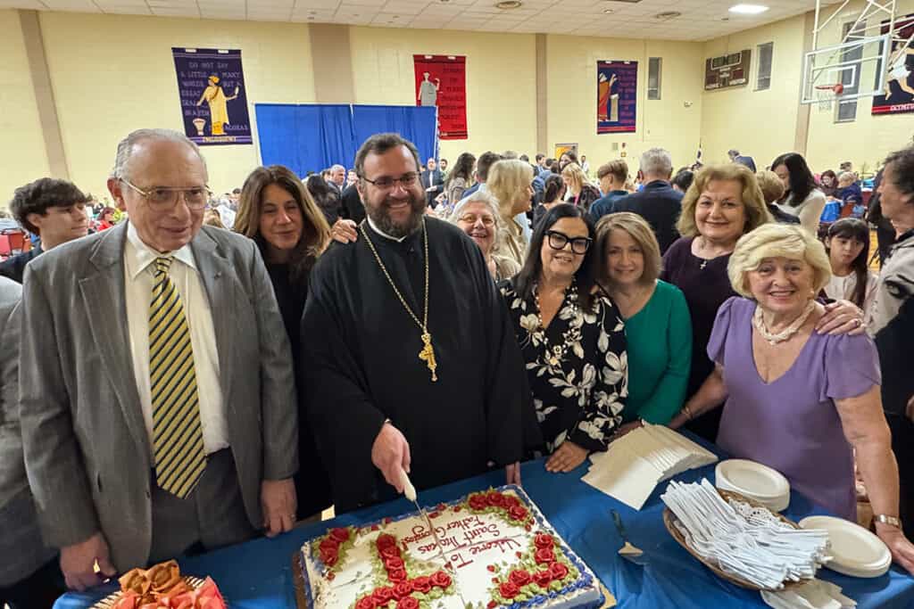 Father Georgios Oikonomou cuts a welcome cake with parishioners during the reception at Saint Thomas Greek Orthodox Church in Cherry Hill, NJ