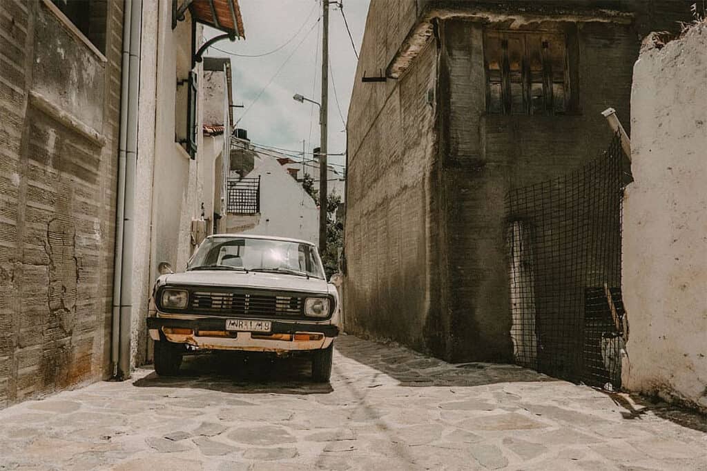 Old car parked in a narrow alley of a Greek village