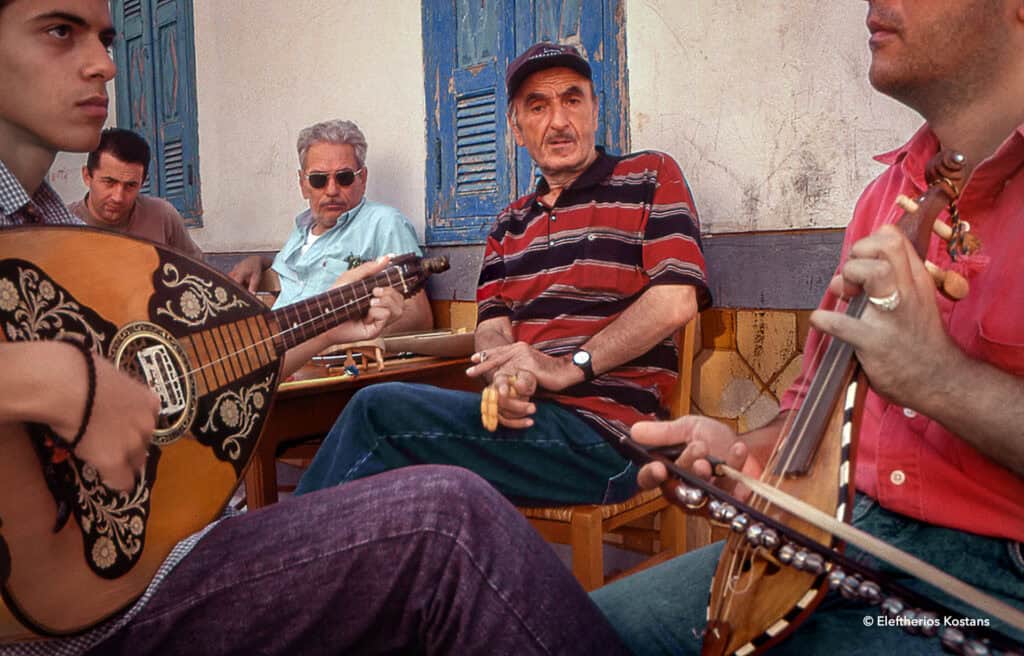 Group of men playing traditional instruments outside a café in Olympos