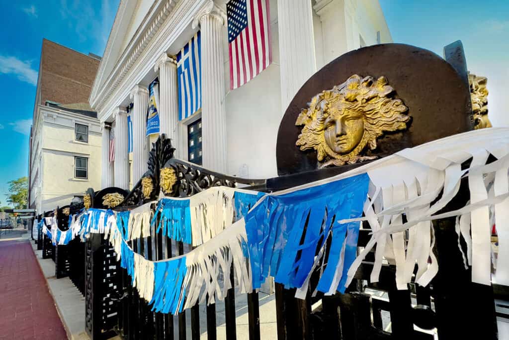 Iron fence of St. George Cathedral decorated with Greek and American flags.