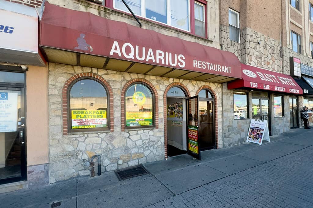 Front view of Aquarius Restaurant on Market Street in Upper Darby with red awning and breakfast signs.