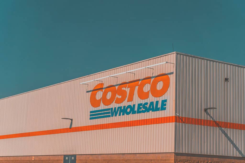 Exterior Costco Wholesale sign on a warehouse building against a blue sky.