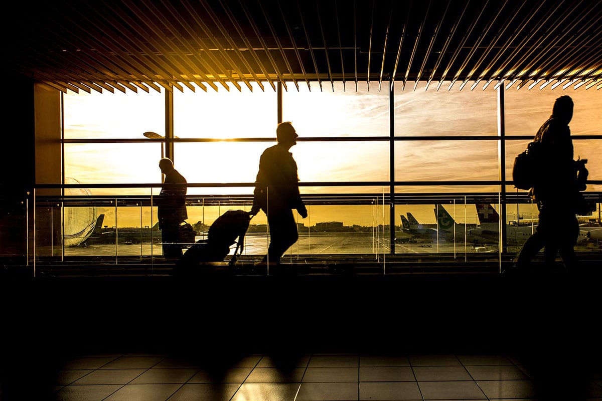 Travelers walking through an airport terminal at sunset as Europe prepares to introduce the new Entry/Exit System
