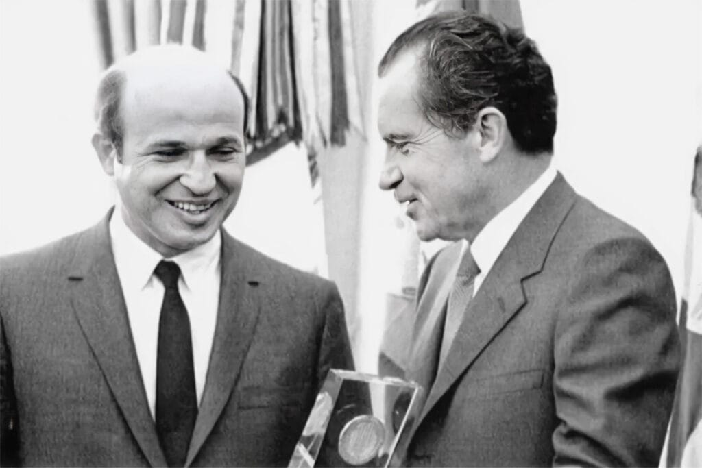 Gene Rossides standing beside U.S. President Richard Nixon during a White House ceremony in the early 1970s, holding an award plaque.