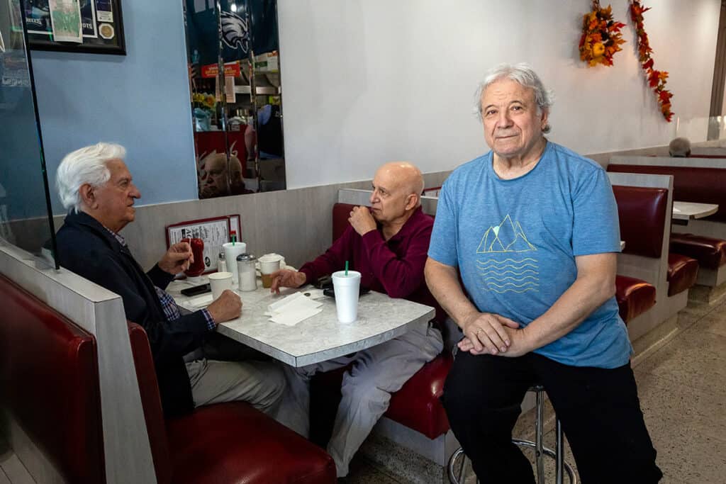John Kontaxis talking with two longtime friends at a booth in Aquarius Restaurant.