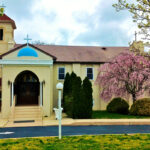 Exterior view of St. Anthony Greek Orthodox Church in Vineland, New Jersey, with blooming trees in spring