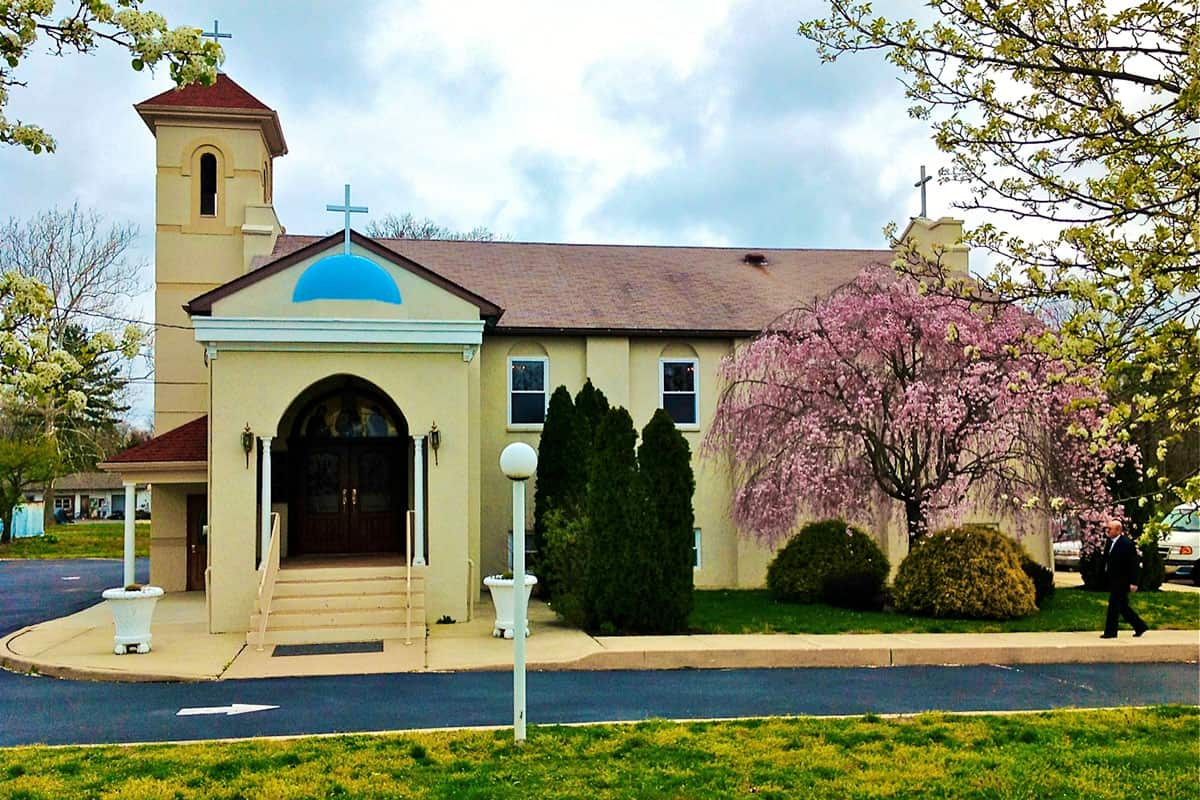Exterior view of St. Anthony Greek Orthodox Church in Vineland, New Jersey, with blooming trees in spring