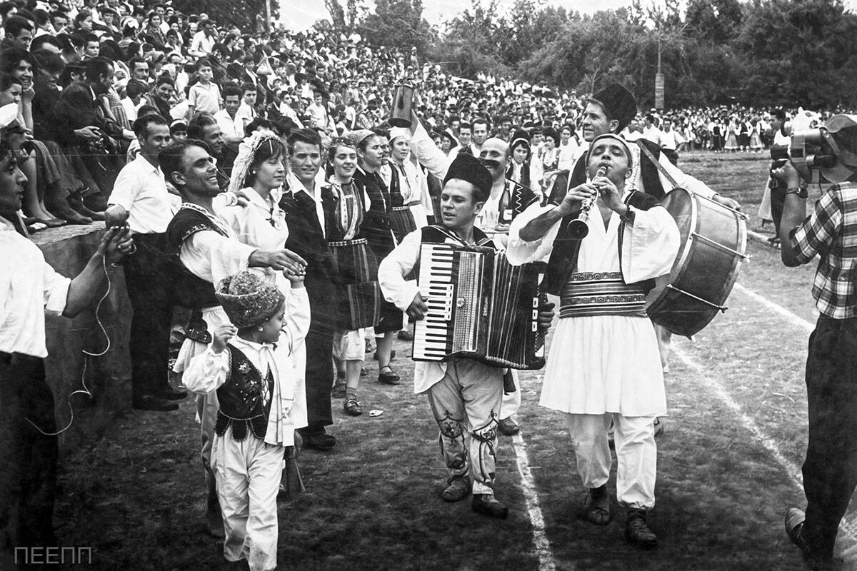 Festival of Greek political refugees in Tashkent in 1963 with musicians and dancers reenacting a traditional Macedonian wedding before a large crowd.