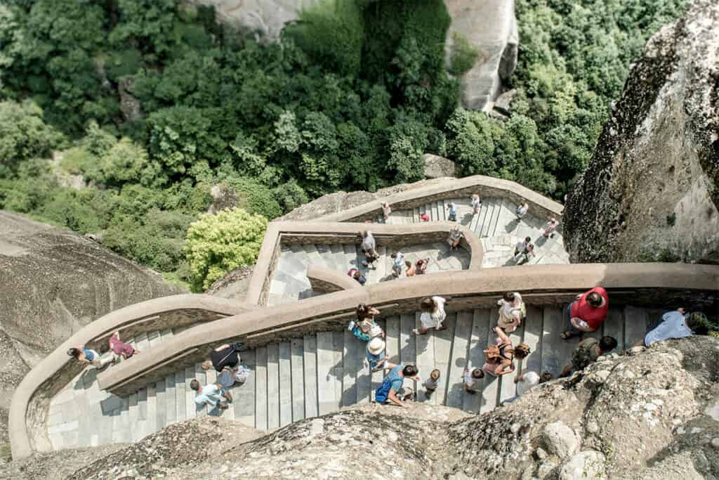 Visitors climbing the stone stairway to a monastery in Meteora, Greece