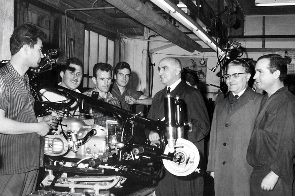 Greek Ambassador Alexis Kyrou and Trade Attaché Gerassimos Papavassiliou visit Greek guest workers on the BMW motorcycle assembly line in 1964.