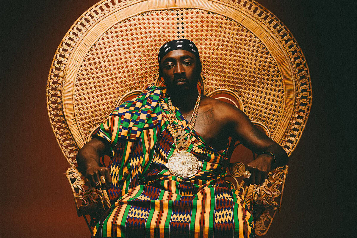 Portrait of Greek rapper Negros Tou Moria wearing traditional patterned fabric.