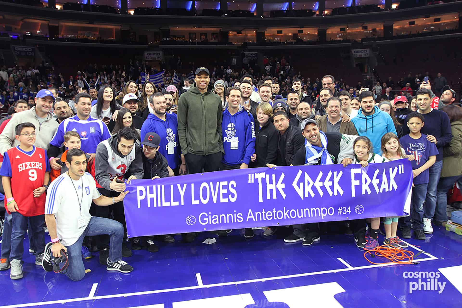 Greek-American fans gather on the Wells Fargo Center court holding a banner that reads “Philly Loves the Greek Freak” during Greek Heritage Night in Philadelphia.