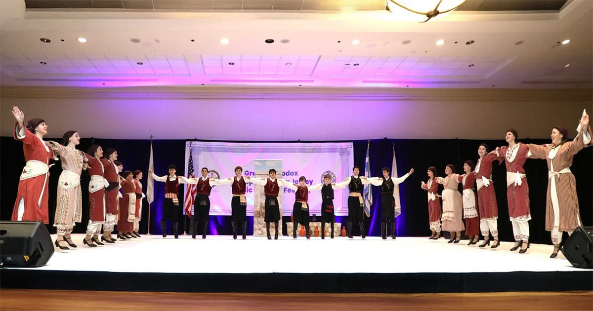 Greek dance group performing on stage during a Music and Dance Festival event.