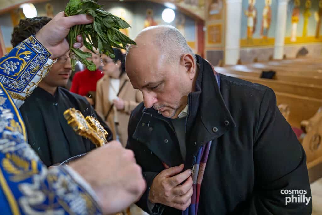 Parishioner receives holy water blessing, bowing in prayer during the service.