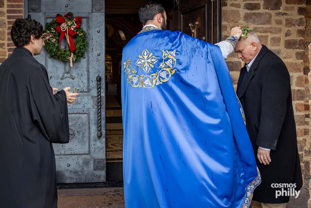 Parishioner bows his head while receiving a personal blessing with basil and holy water.