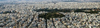 Dense residential apartment buildings across Athens viewed from Lycabettus Hill, illustrating housing density and affordability pressures in Greece.