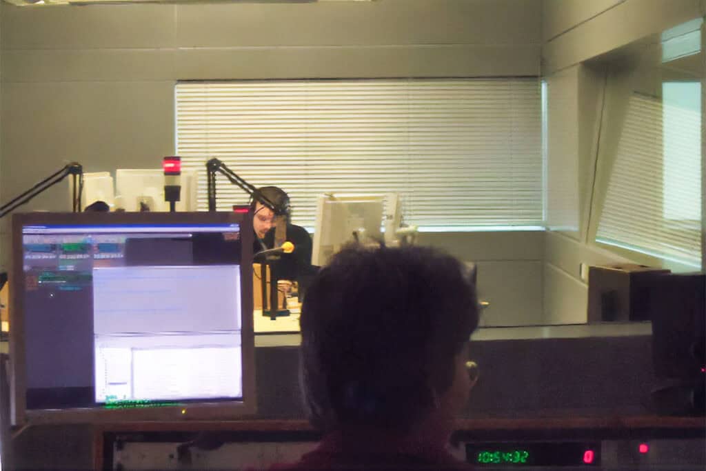 A Deutsche Welle radio studio in Bonn with a presenter speaking into a microphone during a broadcast.