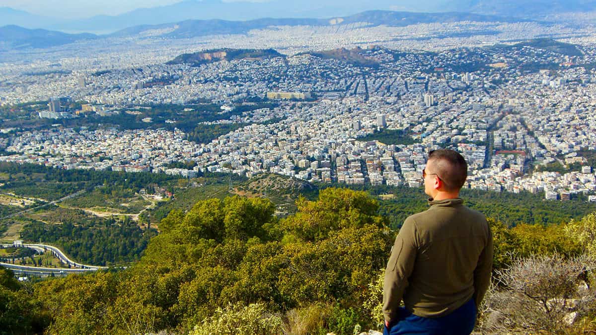 Man overlooking Athens cityscape from a hilltop viewpoint
