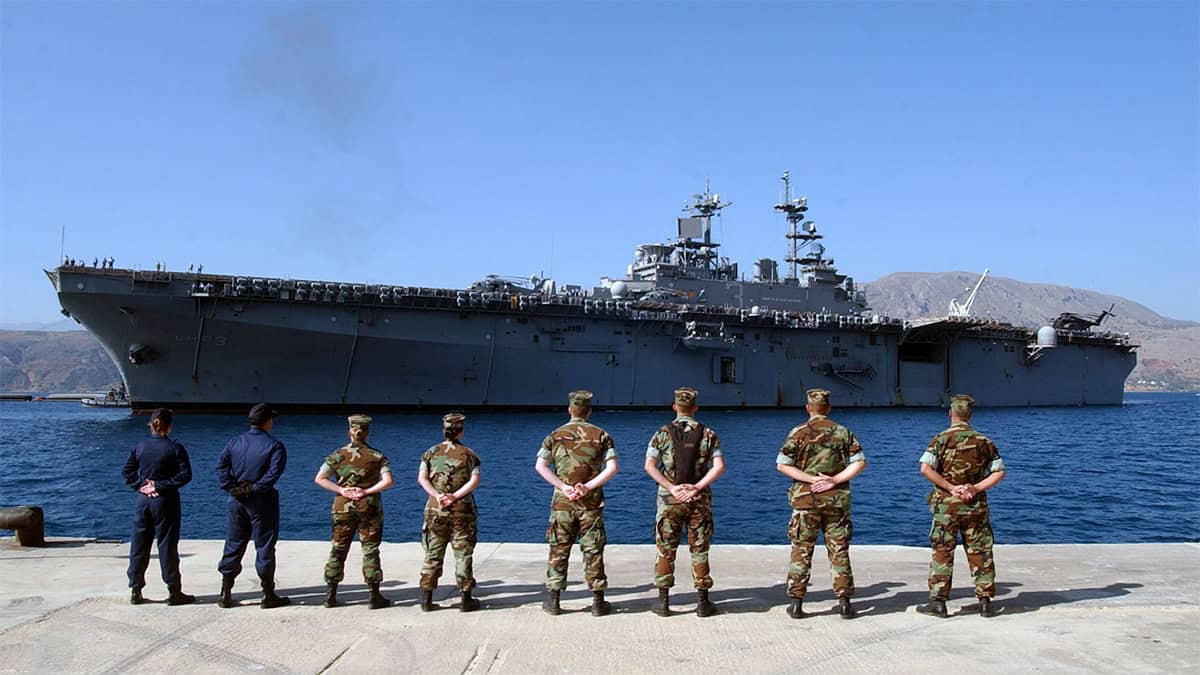 U.S. Navy personnel stand on the pier at Naval Support Activity Souda Bay, Crete, as the amphibious assault ship USS Kearsarge arrives, July 2004.