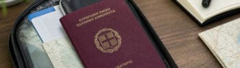 Greek passport partially visible inside a travel pouch on a desk.