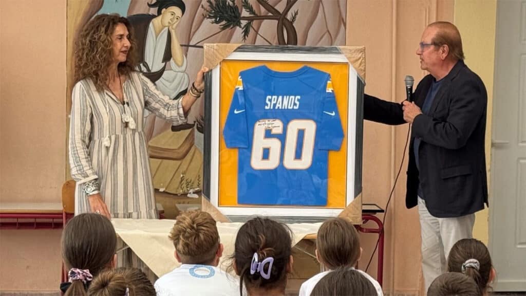 Dean Spanos presenting a signed Los Angeles Chargers jersey to the principal of the elementary school in Eva, Messinia.