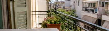 House keys on a balcony table overlooking a Greek apartment neighborhood,