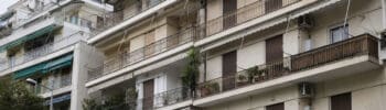 Older apartment building in Greece with closed shutters and balconies