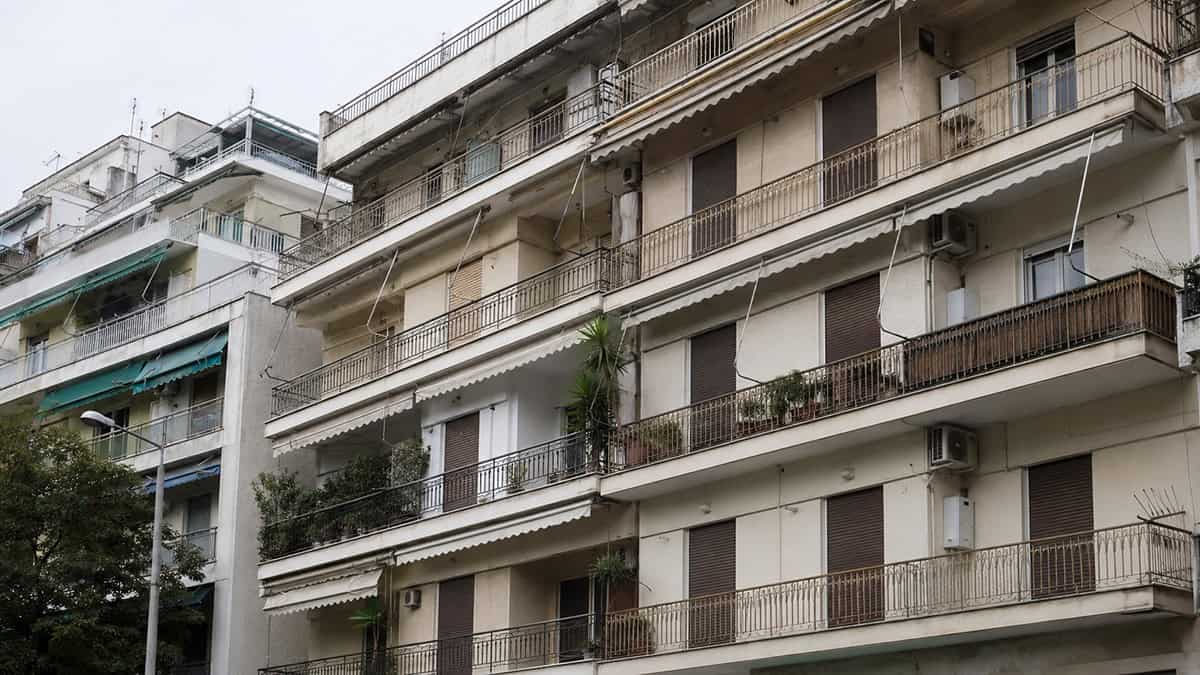 Older apartment building in Greece with closed shutters and balconies