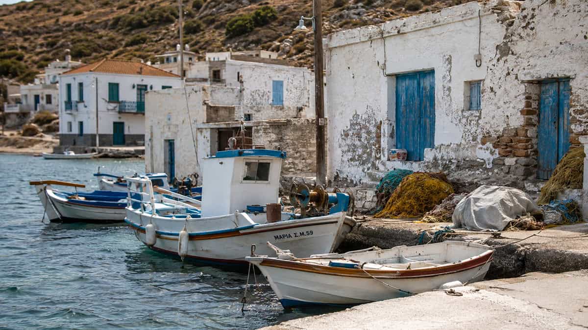 Small working fishing boats tied to a weathered quay in a Greek coastal village