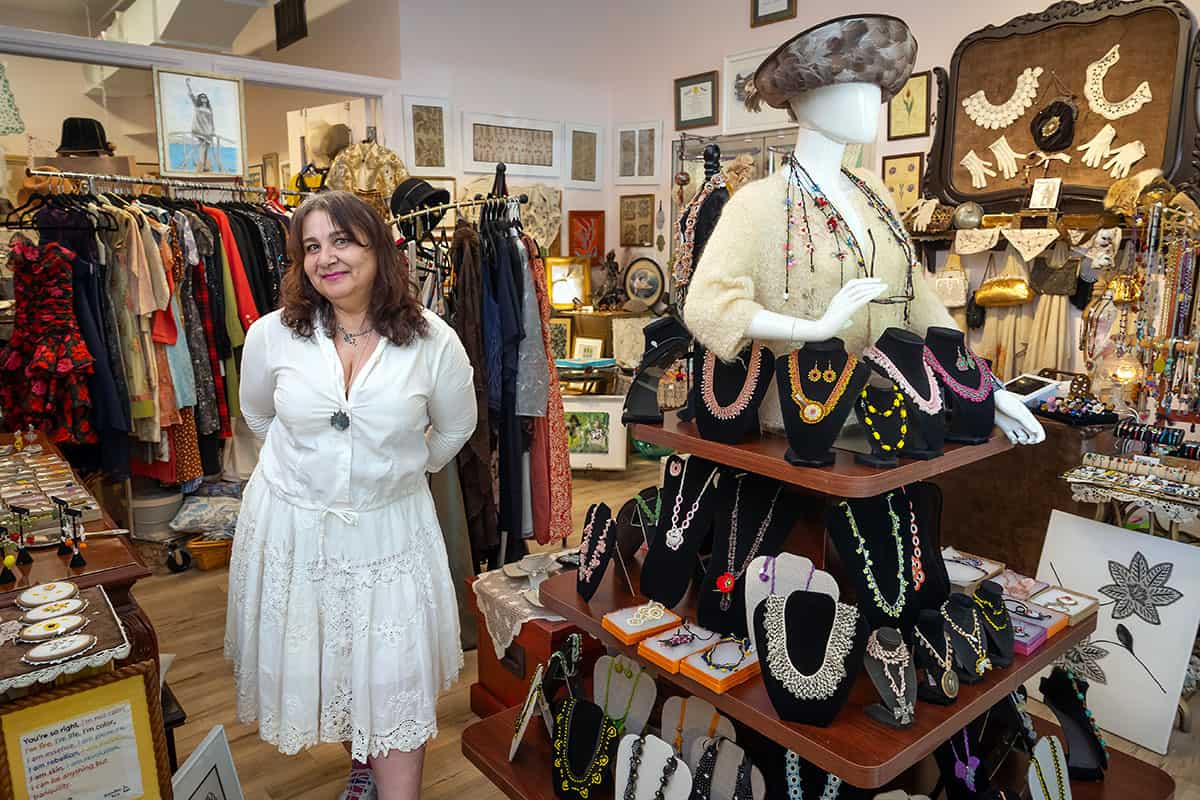 Ylvia Asal stands in her Haddonfield studio surrounded by handmade Oya jewelry, textiles, garments, and artwork.