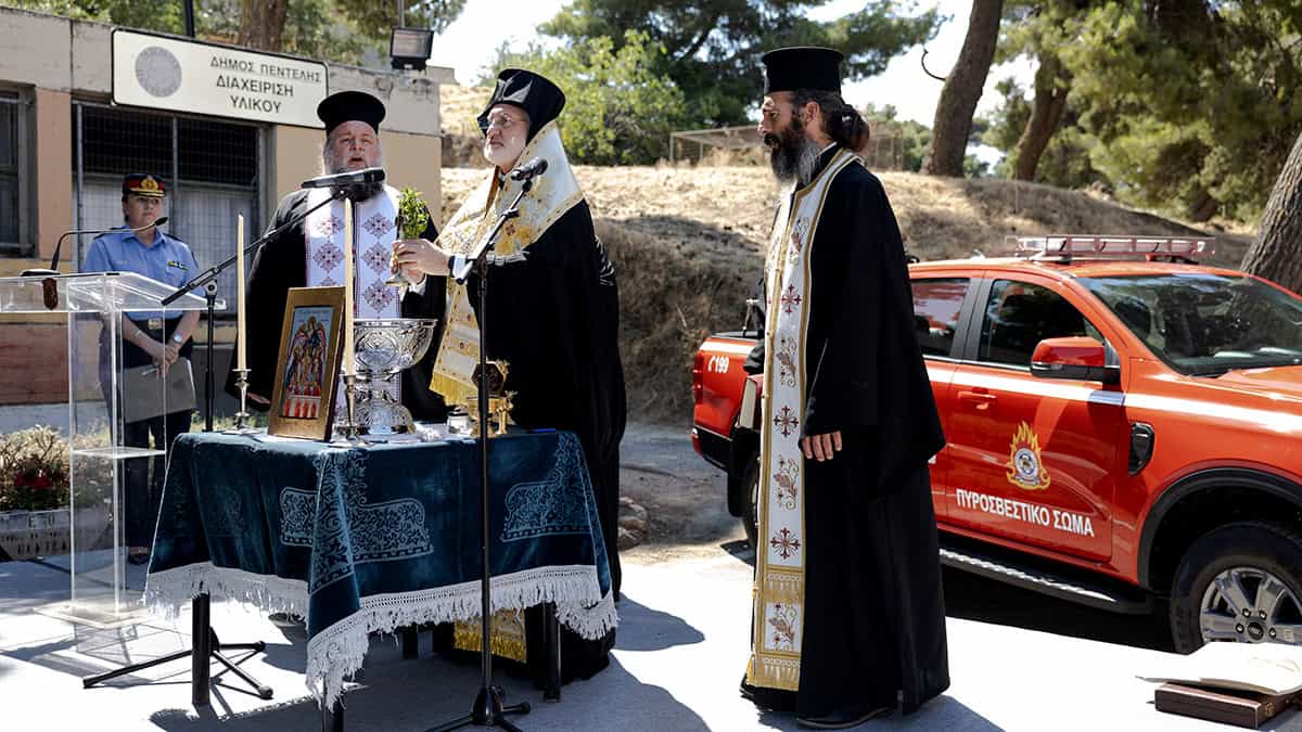Archbishop Elpidophoros blesses a red firefighting vehicle in Penteli, Greece.