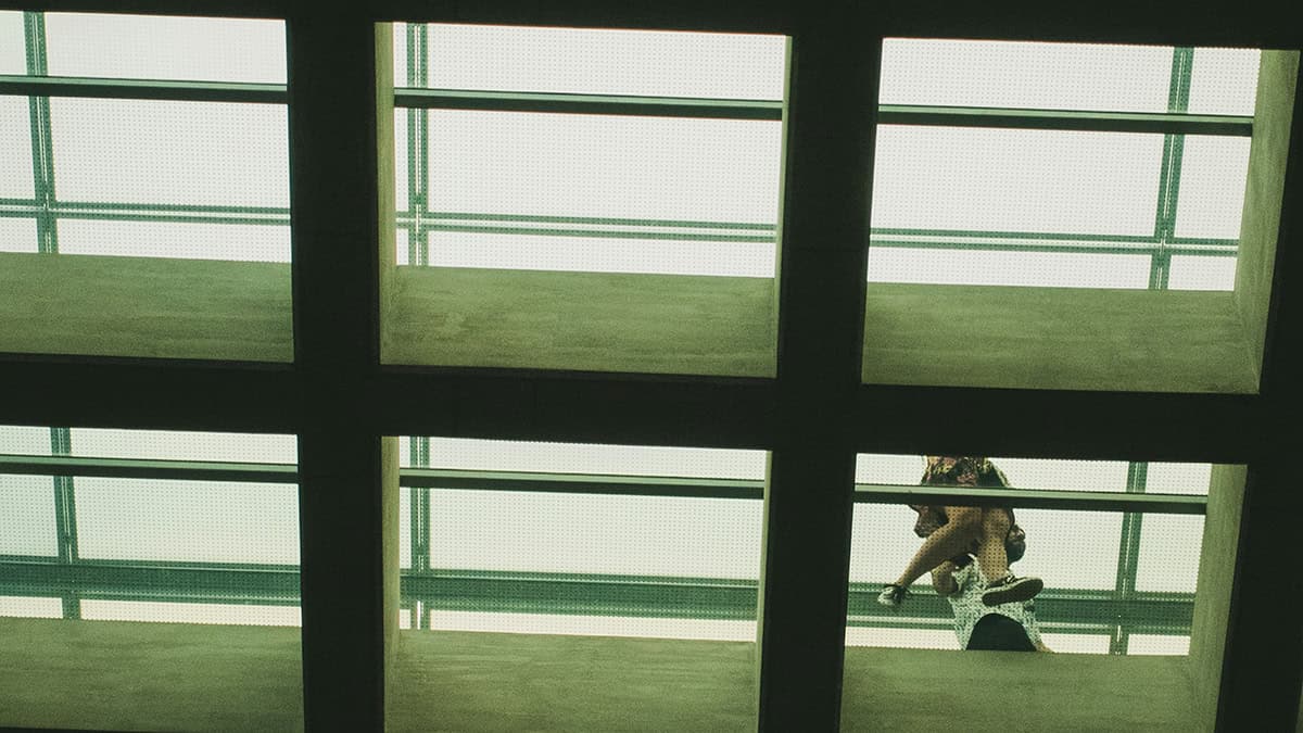 A person walking through the shadowed interior of a modern building in Athens.