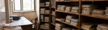 An old archive office with shelves of bundled paper records and worn folders.