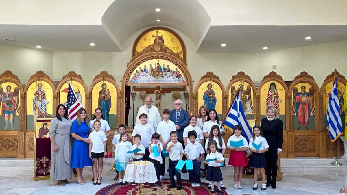 Aristotle Academy students and educators inside St. George Greek Orthodox Church in Media, Pennsylvania, with Greek and American flags.