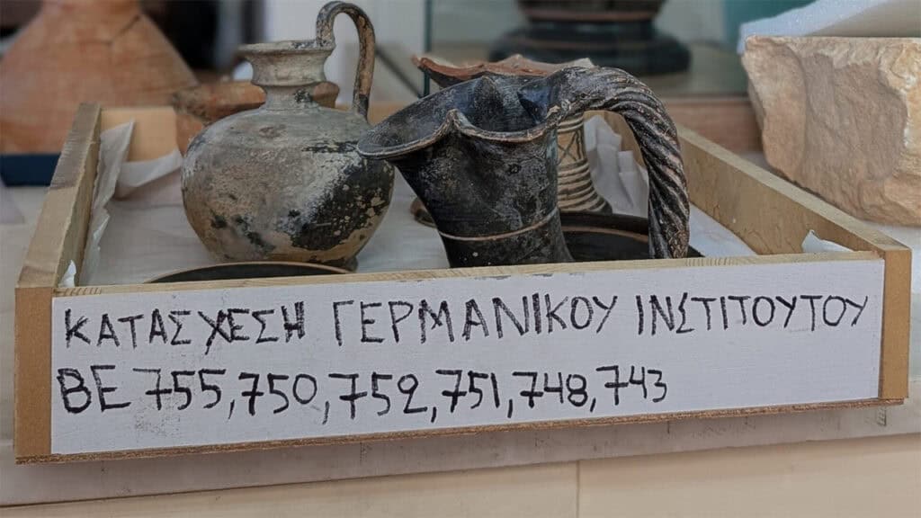 Ancient pottery vessels in a tray labeled as confiscated from the German Archaeological Institute in Athens.
