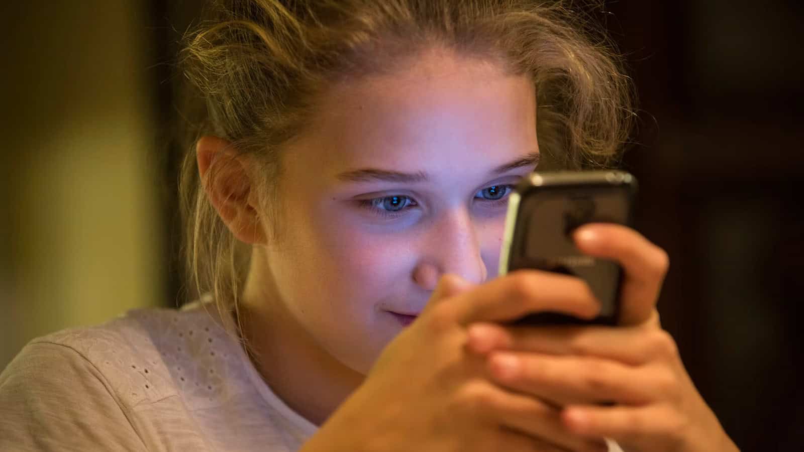 Young girl looking at a smartphone held in both hands